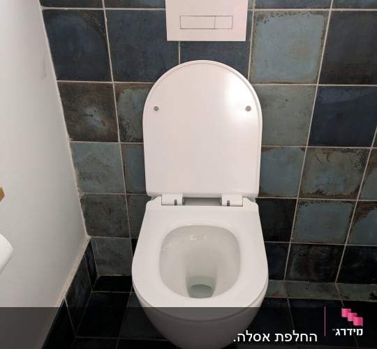 אסלה תלויה לבנה עם ניאגרה סמויה ולחצן הדחה על קיר אריחים כחול